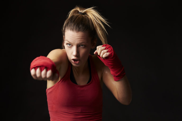 Young blonde woman shadow boxing, throwing a punch
