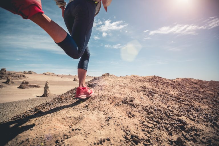 Fitness woman trail runner cross country running on sand desert
